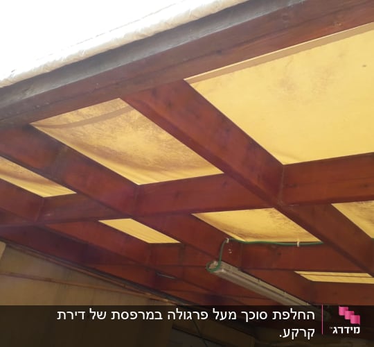 סוכך עץ עם לוחות בד צהובים מתוחים